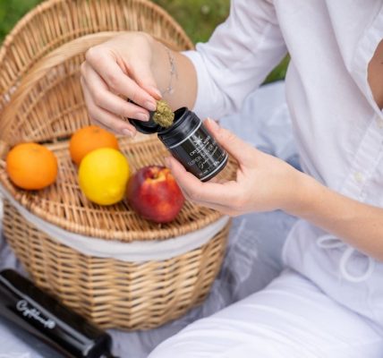 two women sitting on the grass with a basket of fruit