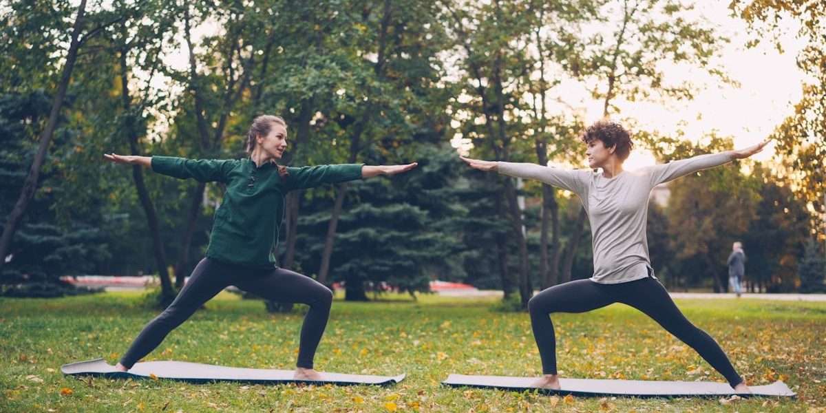 Pretty women is trendy sports clothing are training outdoors doing yoga enjoying movement, fresh air and warm autumn weather. Sports, leisure and youth concept.