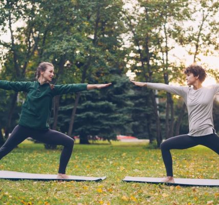 Pretty women is trendy sports clothing are training outdoors doing yoga enjoying movement, fresh air and warm autumn weather. Sports, leisure and youth concept.