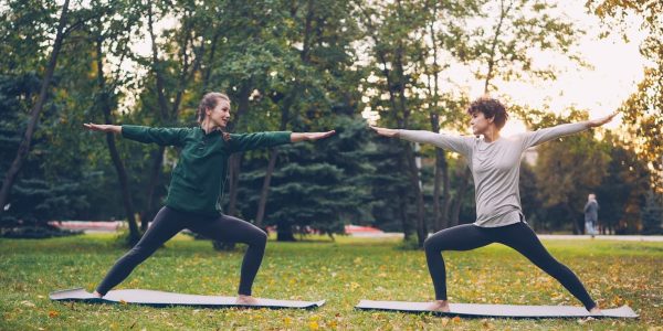 Pretty women is trendy sports clothing are training outdoors doing yoga enjoying movement, fresh air and warm autumn weather. Sports, leisure and youth concept.